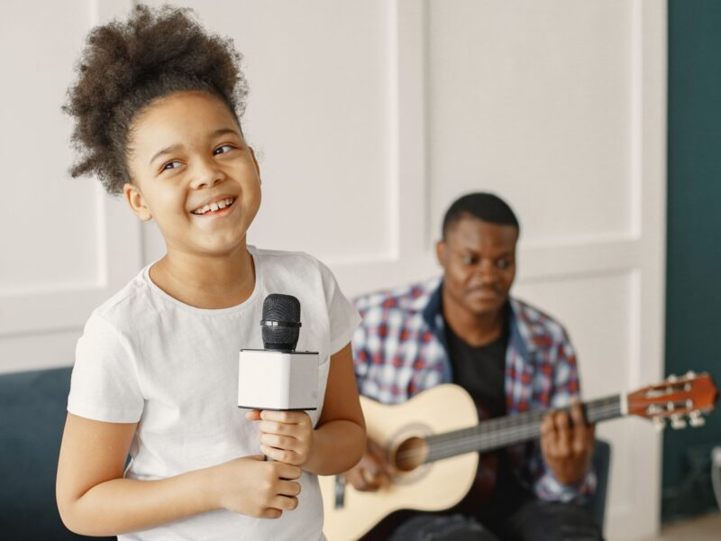 Girl singing with microphone and therapist playing guitar